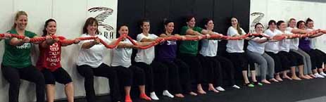 A Battle Girl Bootcamp conditioning drill — a wall-sit hold — at Rumble Martial Arts.