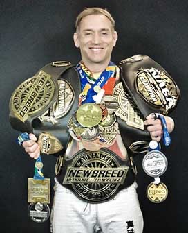 Rumble's head instructor wearing championship belts and medals from international competition.